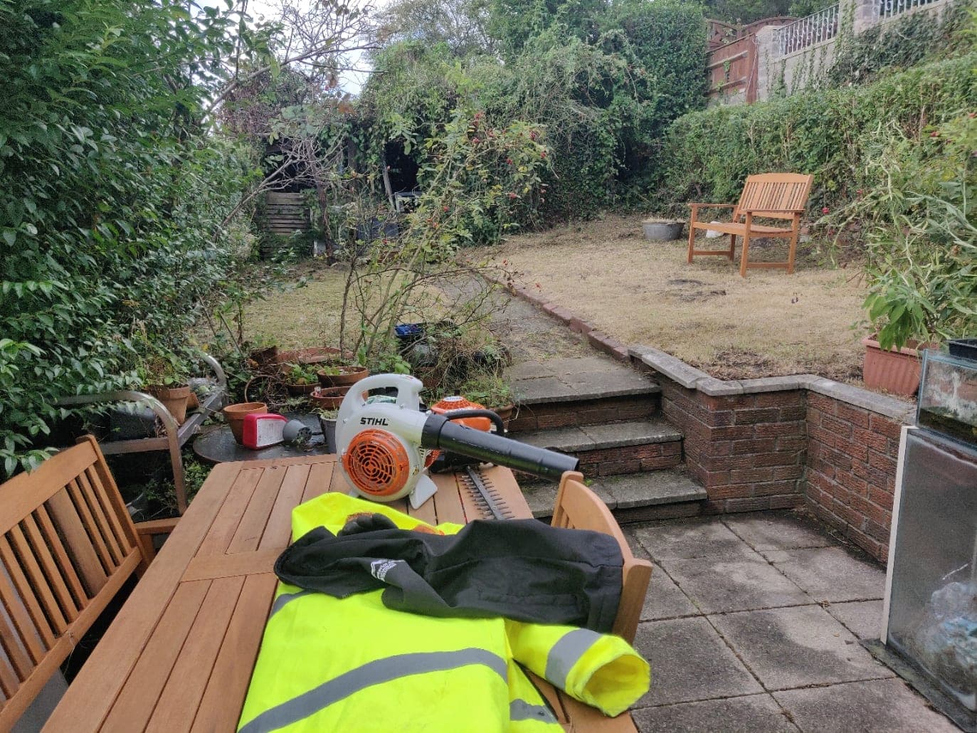 Hi-vis jacket and a Stihl blower on a garden table part-way through a job